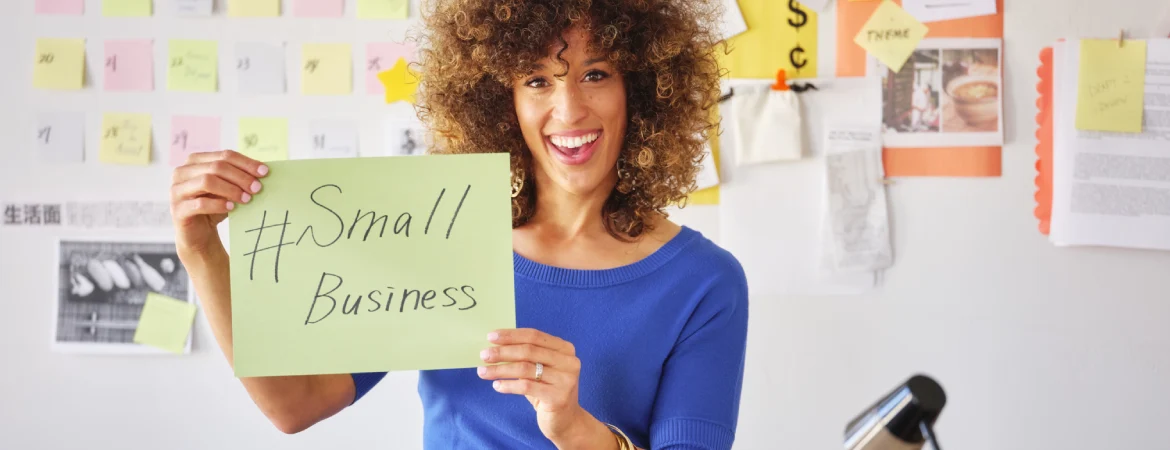 Kobieta trzymająca kartkę z&nbsp;napisem "mała firma"